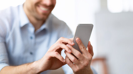 Technology Concept. Closeup of smiling man holding mobile phone, selective focus on device, copy space