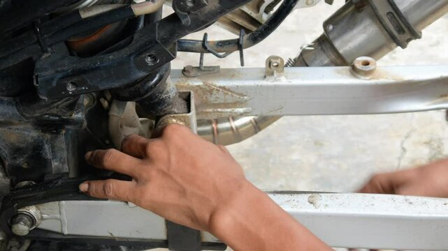 A mechanic's hand opens a motorcycle shockbreaker bolt for maintenance, repair and service