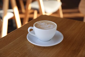 Cup of aromatic coffee on wooden table in cafe