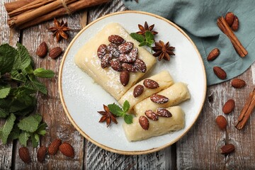 Delicious sweet semolina halva with almonds, spices and mint on wooden table, flat lay