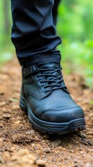 Close-up of a sturdy black boot on a forest trail surrounded by greenery