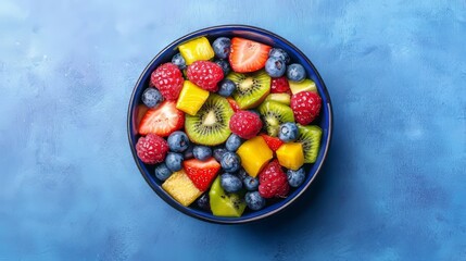 Colorful fruit salad in blue bowl on textured surface