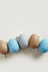 Elegant Easter Composition with Pastel Eggs and Spring Blossoms, still life Dyed eggs in soft pastel colors, top view spring holiday minimal creative pattern, neutral earth colored image, above