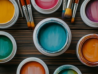 Colorful paint jars and brushes arranged on a wooden surface for artistic projects