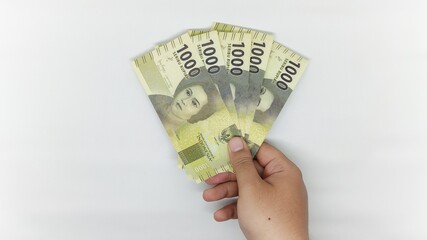 hand holding new Indonesian banknotes in the 1000 rupiah denomination