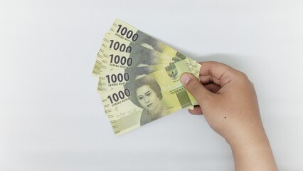 hand holding new Indonesian banknotes in the 1000 rupiah denomination