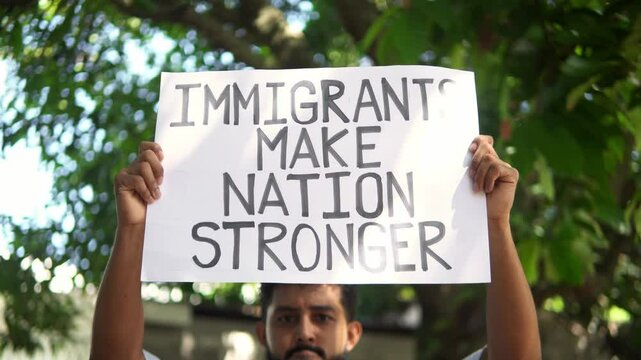 Hispanic man holding sign supporting immigrants