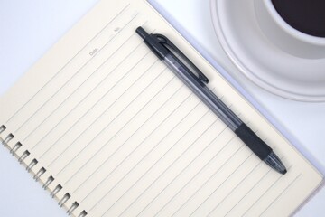 Cup of coffee, notebook and pen on white table