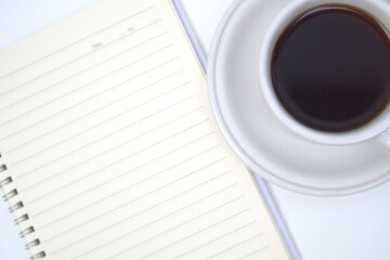 Cup of coffee, notebook and pen on white table