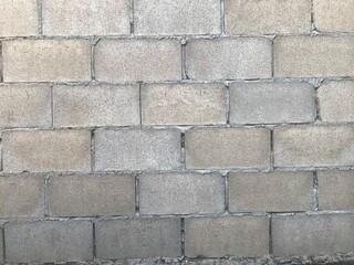 A close-up view of a concrete block wall.The blocks are rectangular and arranged in a regular...