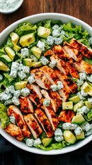 Grilled chicken salad with fresh greens, cucumbers, and avocado on a wooden table
