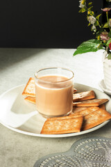a glass of milk tea with biscuits on a plate