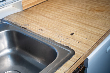 1970s vintage kitchen, looking down at stainless steel sink and wood grain laminate counter tops...