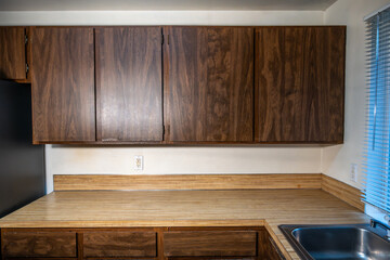 1970s vintage kitchen, dark brown cabinets, wood grain laminate counter tops, white walls, rental home interior damage after the tenant moves out, housing market
