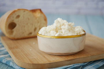 Fresh cottage cheese and bread on a wooden cutting board