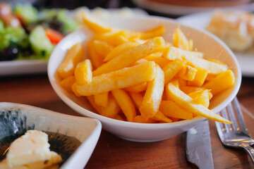 Crispy golden fries served in a bowl with fresh meals beside