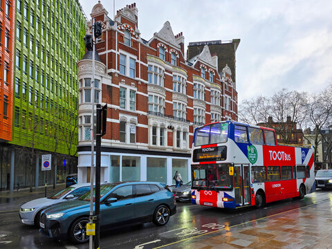 a red, white and blue double decker TOOT Bus driving on the street on the westside in London England UK