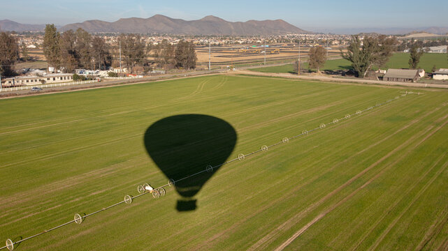 Hot air balloon shadow over freshly cut alfalfa field seen from aerial viewpoint in Temecula southern California United States