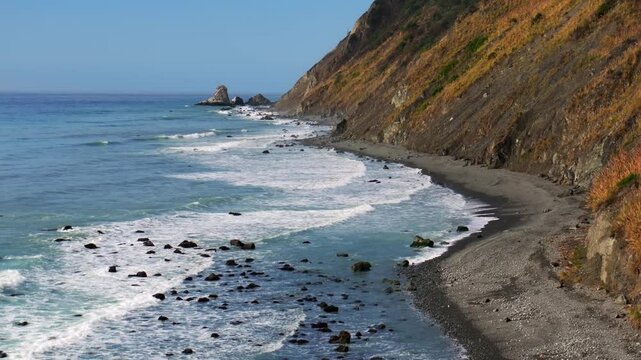 Waves crashing surf black sand rugged coastline sunny morning blue sky mist fog layer USAL Beach Campground Lost Coast Trail California Pacific Ocean PNW boulders rocks mountainside backwards motio