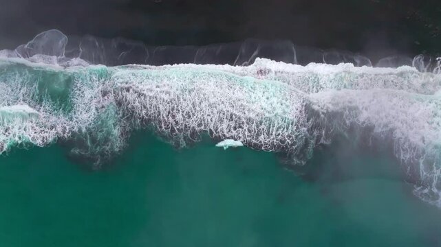 Waves crashing black sand boulder rocks rugged coastline USAL Beach Campground Lost Coast Trail California Birdseye aerial drone fog mist rain cloudy layers morning Pacific Ocean left motion