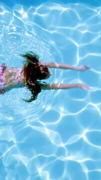 Overhead of brunette swimming in pool on sunny day