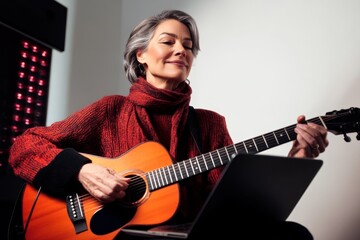 Obraz premium Senior woman playing guitar and enjoying music at home during cozy indoor afternoon