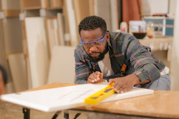 Affrican American male carpenter work with cralf paper in furniture factory, Black labor man using...