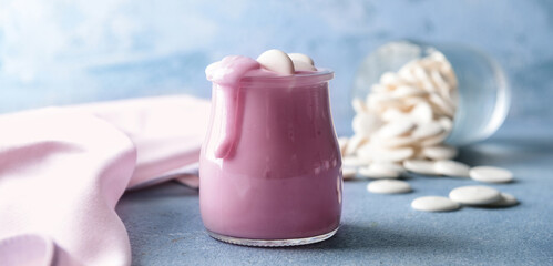 Jar with tasty yogurt and chocolate chips on color table