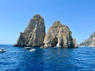 Obraz premium Faraglioni rocks in Capri with boats on blue sea.