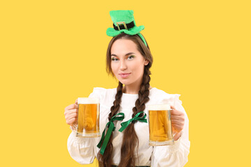 Happy woman with beer celebrating St. Patrick's Day on yellow background