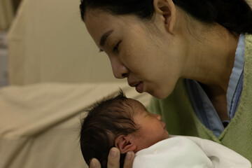 A woman is holding a baby in her arms. The baby is wearing a hat and a blanket. Concept of warmth and love between the mother
