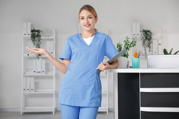 Female medical intern with clipboard near reception in clinic