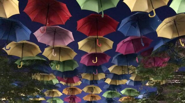 Street at Coral Gables decorated with colored and open umbrellas, people enjoying the decoration.