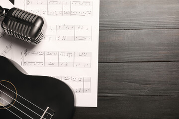 Ukulele, microphone and music sheets on dark wooden background