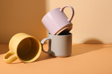 Beautiful ceramic mugs on orange background