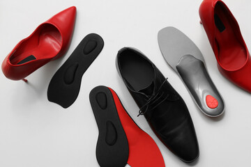 Different shoes with orthopedic insoles on light background