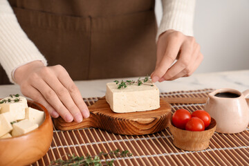 Woman with tasty tofu cheese on table