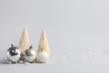 Silver baubles with beads garland and mini Christmas trees on grey background © Pixel-Shot
