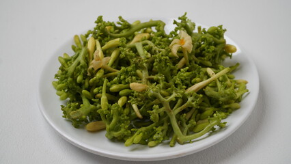 A collection of raw papaya flowers placed on a white plate with a white base and background (isolated white).