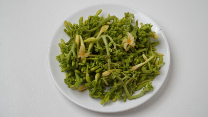 A collection of raw papaya flowers placed on a white plate with a white base and background (isolated white).
