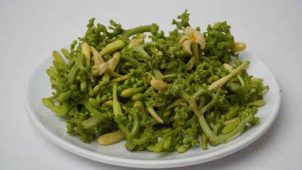 A collection of raw papaya flowers placed on a white plate with a white base and background (isolated white).