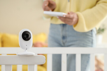 Baby monitor on crib against woman in children's bedroom, closeup