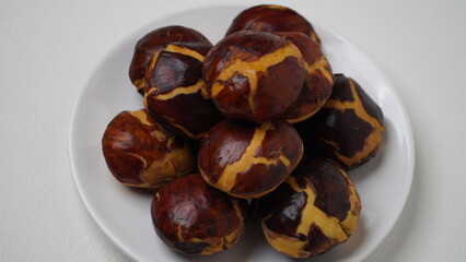 A collection of raw jengkol placed on a white plate with a white base and background (isolated white).