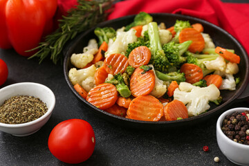 Frying pan with tasty roasted vegetables on black background, closeup