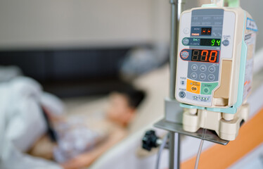 Asian boy lying on sickbed with infusion pump intravenous IV drip 
