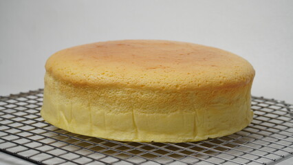 A whole Japanese Cheese Cake placed on a cooling rack with a white base and background (isolated white).
