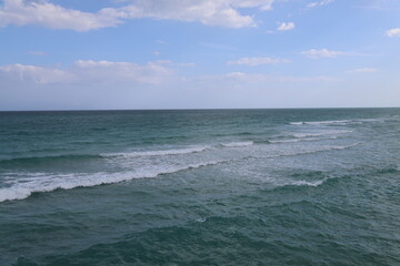 Rolling waves with white foam in the ocean green blue water
