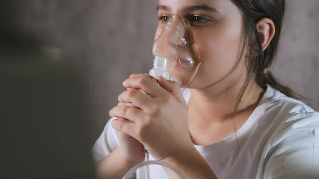 Little girl using nebulizer mask for inhalation therapy at home.