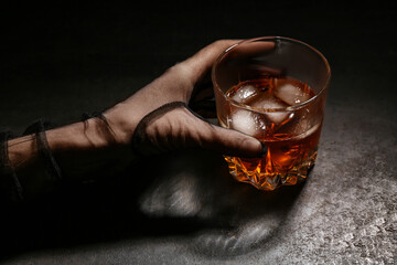 Female hand in mesh glove holding glass of cold rum on black grunge background
