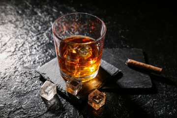 Glass of cold rum and cigars on black grunge background